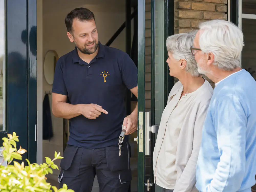 Monteur geeft een ouder echtpaar de nieuwe sleutels en legt de veiligheidscilinder uit